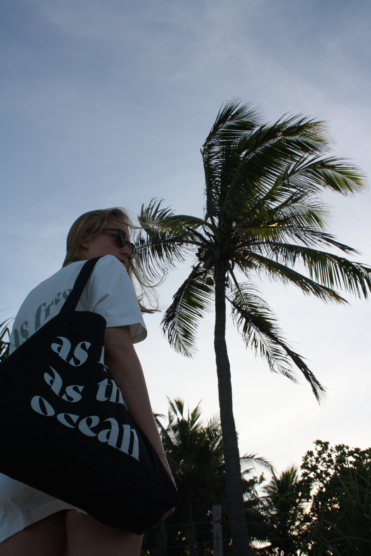 Model wearing AFATO beachbag with motivational print – 'As Free As The Ocean' – perfect for storing your surf gear and beach essentials.