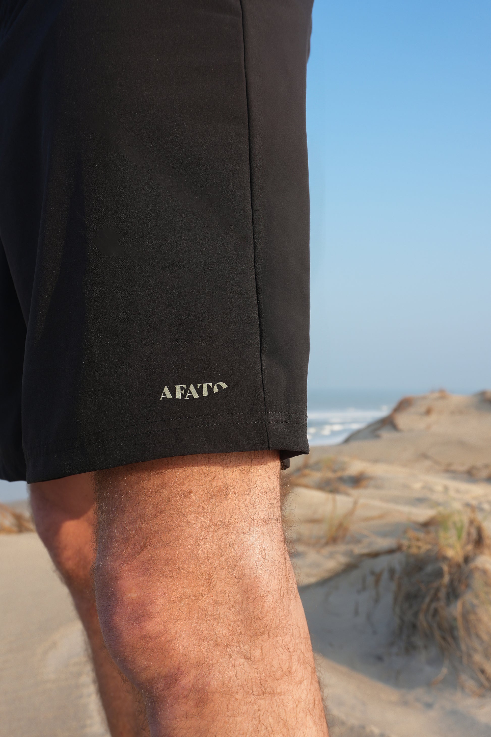 Close-up of AFATO boardshorts in black logo detail – highlighting the brand logo and premium surfwear quality.