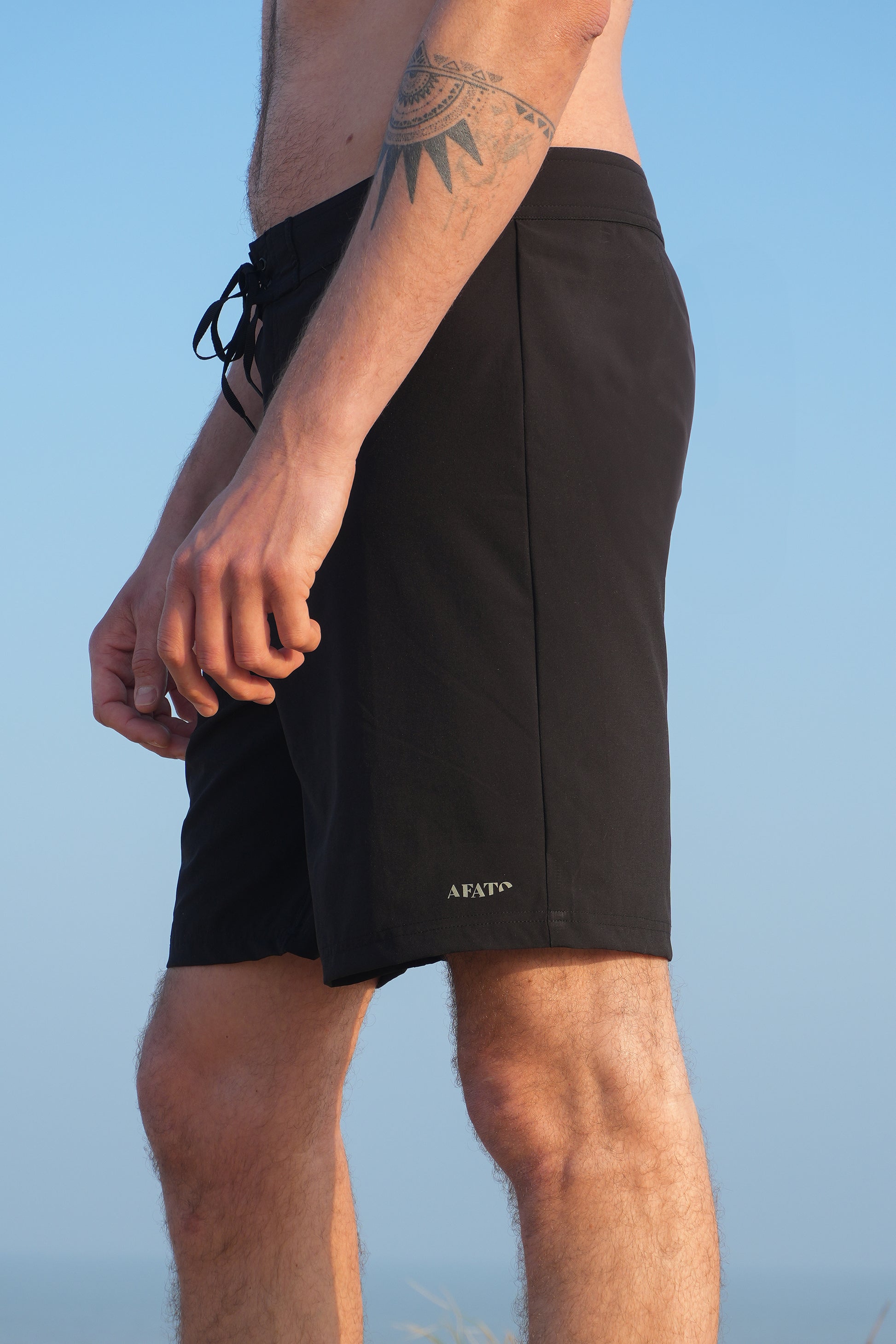 AFATO boardshorts in black – side view showcasing a streamlined silhouette designed for surfing and movement.