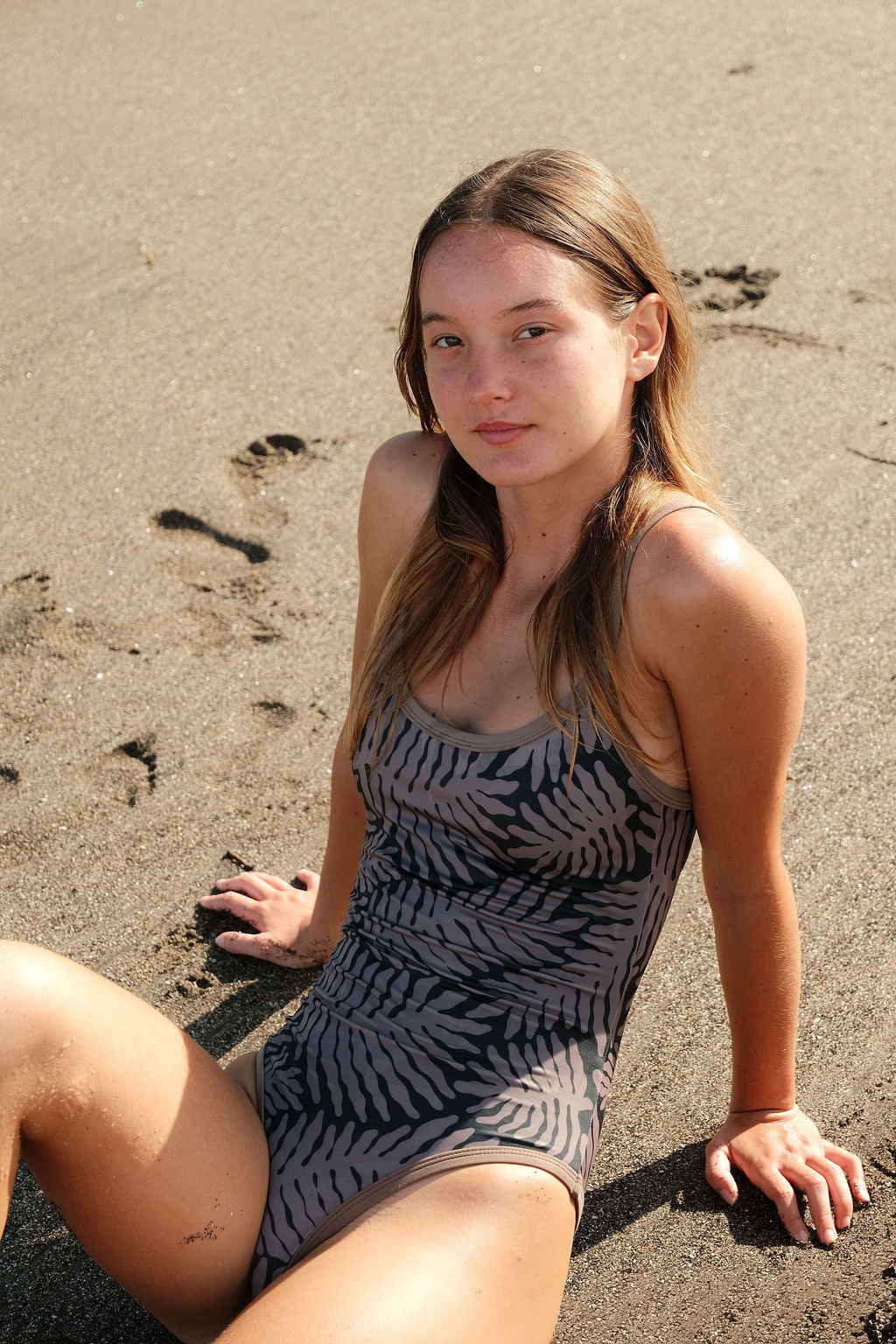 Model wearing AFATO Oceansuit in Palm Rhythm print at the beach.