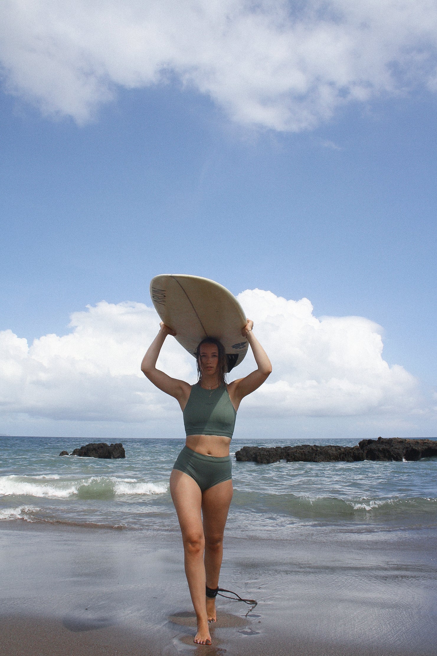 AFATO surfwear set in action: model with surfboard on head, ready for the waves.