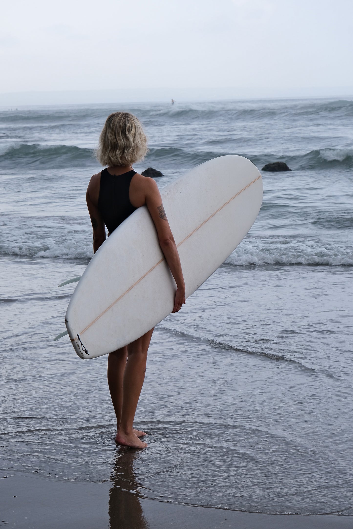 AFATO surfwear set in action: model with surfboard, ready for the waves.