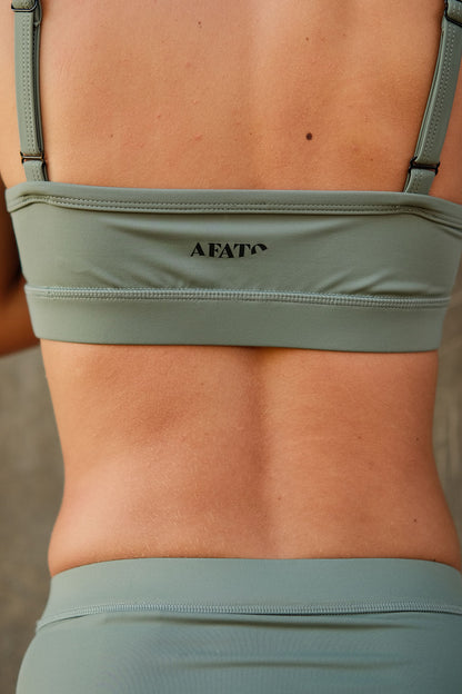 Close-up of AFATO V-neck top in sage green fabric – highlighting soft texture, stretch, and premium quality.